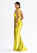 Side view of a black woman wearing a yellow floor-length stretch satin bridesmaids gown with an asymmetrical knotted neckline and ruched bust.  Dress shows curves!