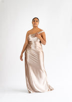 Aura champagne stretch satin one-shoulder bridesmaid dress with a draped bodice, shown on a curvy model