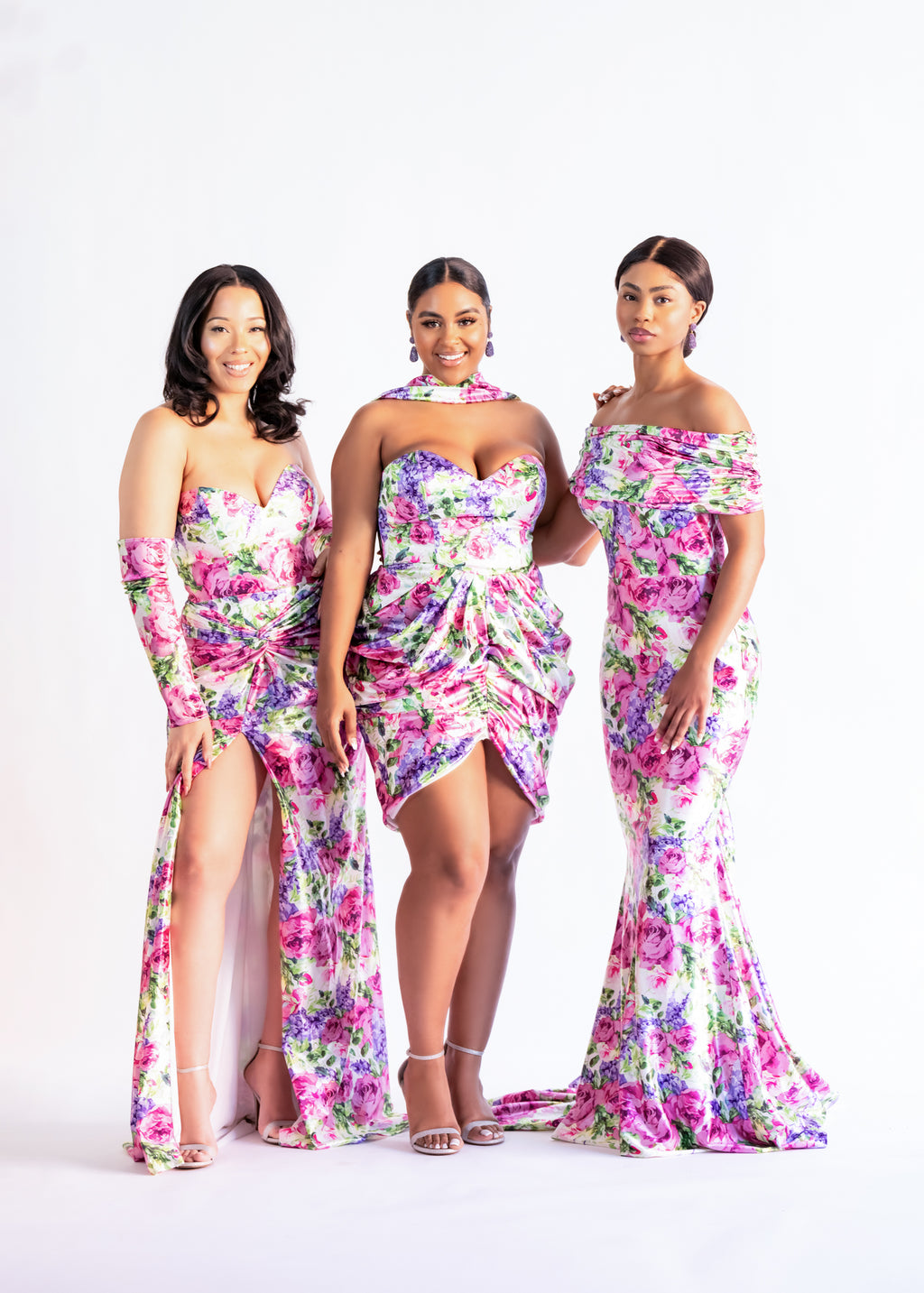 Three bridesmaids in pink and purple floral print dresses, including the Livvy draped mini with neck scarf