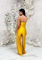 Bridesmaid wearing a modern strapless fitted bridesmaid jumpsuit with stretch. Style has a curved architectural detailing at the neck and is shown in a golden vibrant yellow on a black model.