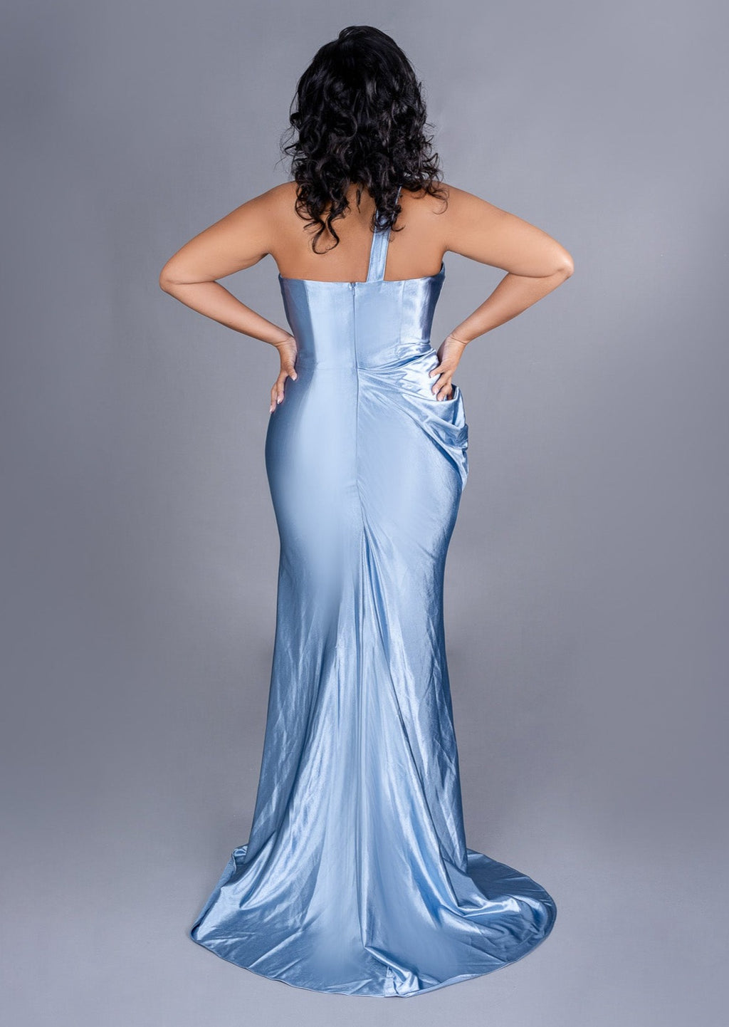 Fitted stretch satin bridesmaid dress with one shoulder detailing, ruching, and keyhole neckline on plus size curvy model - back view