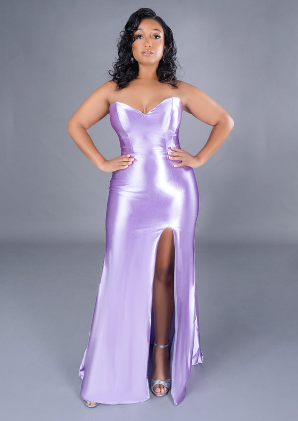 Curvy plus size bridesmaid wearing a strapless fitted bridesmaids dress with stretch. Dress has a slit at the leg and is shown on a plus size model.