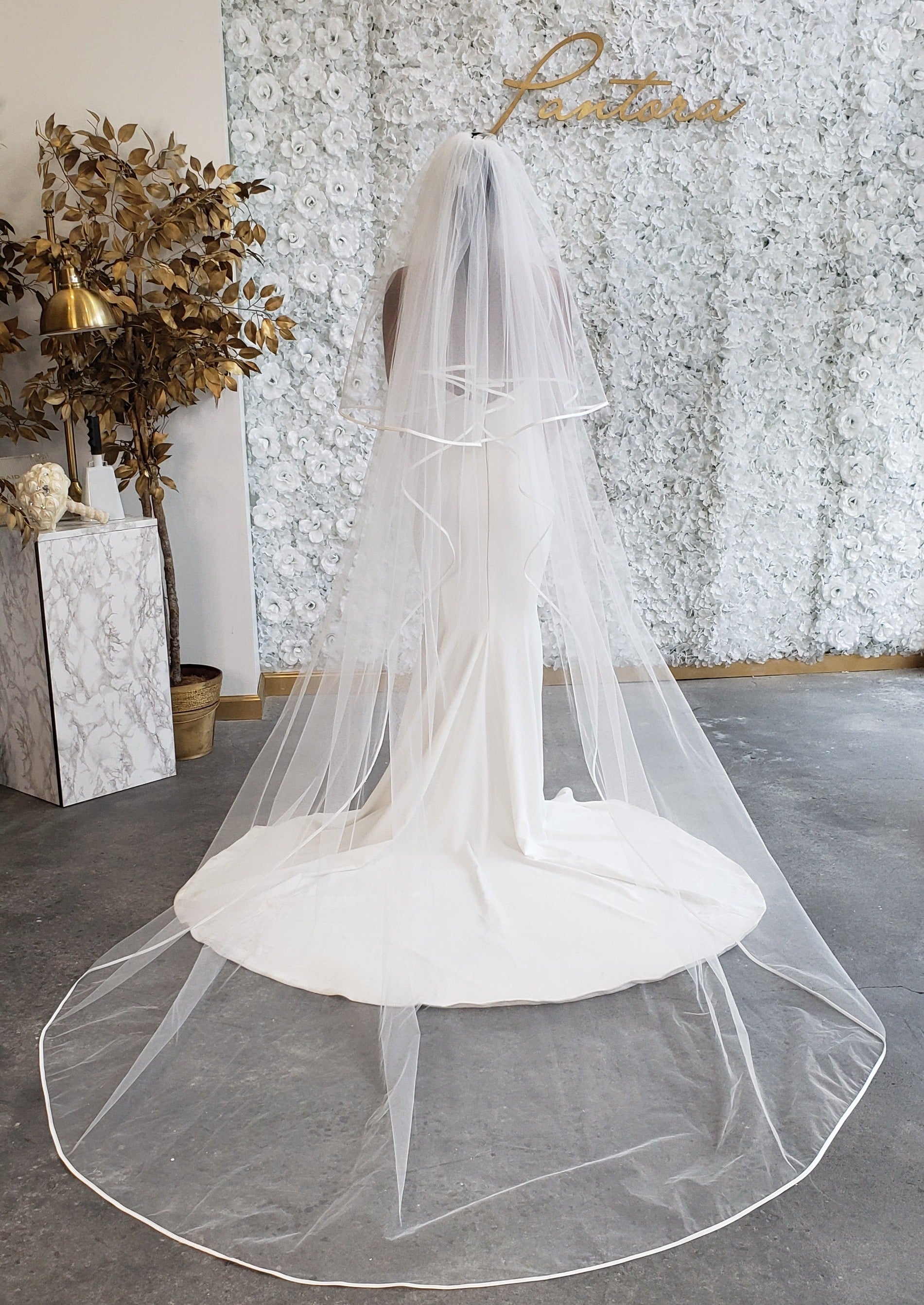 Mesh Veil with ribbon edge paired with clean off white bridal gown. the veil is embellished by a satin ribbon trim. The veil is clean with a soft touch that makes a statement with cascading movement and optional blusher. 