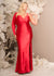 Plus size bridesmaid wearing a fitted V-Neck bridesmaid dress with an asymmetrical Dolman sleeve, gathering, and gentle draping. Shown in a vibrant red, this style features a leg slit and is made in stretch satin to flaunt curves