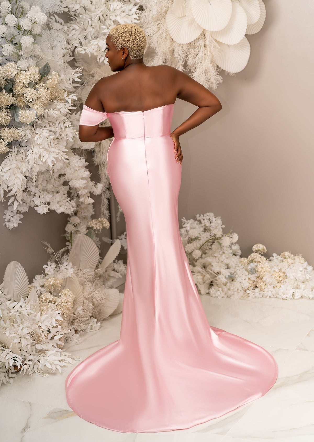 Plus size black model wearing a stretch satin bridesmaid dress with sweetheart neckline, leg slit, and sweeping train - back view