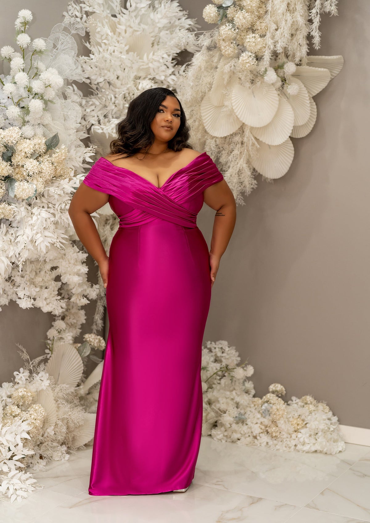 Plus size curvy black bridesmaid wearing a column off the shoulder bridesmaid dress with crisscross pleating and stretch to flaunt curves