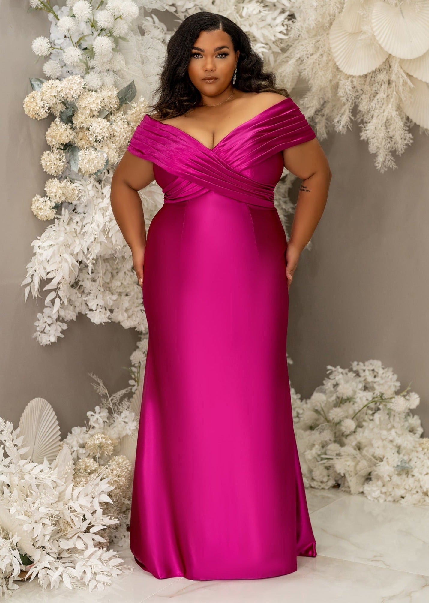Plus size curvy black bridesmaid wearing a column off the shoulder bridesmaid dress with crisscross pleating and stretch to flaunt curves
