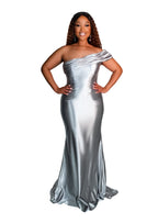 Full-length metallic asymmetrical bridesmaid dress with a fitted silhouette and draping across the neckline into an off-the-shoulder strap. Featuring stretch satin, this style is designed to flatter and complement all body types. Shown on a black curvy model.